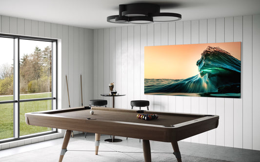 A dramatic ocean wave rises at sunset, glowing with golden and teal tones. A striking fine art surf photograph highlighting fluid motion and evening light.