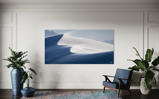 A serene fine art photograph of wind-shaped sand dunes glowing in soft sunrise light. Elegant curves and flowing shadows create a peaceful desert landscape.