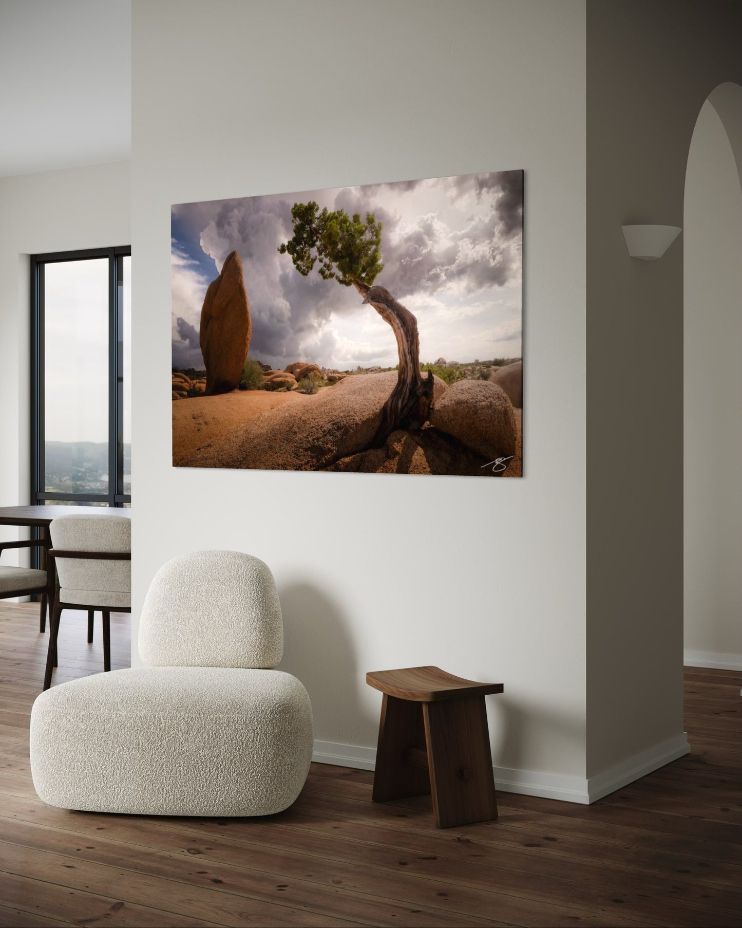 A twisted juniper tree stands against dramatic monsoon storm clouds in Joshua Tree National Park. A striking California desert fine art landscape.