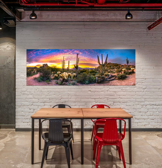 A vivid Sonoran Desert sunrise ignites the sky above towering saguaros and glowing cholla. A sweeping fine art panorama capturing Arizona’s desert beauty.