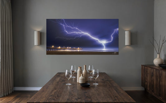 Art mounted on a wall displaying a lightning storm, with a dining table and decor in the foreground.