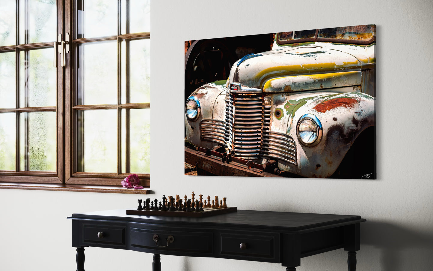 Vintage car painting on a wall above a black console table with a chessboard.