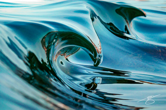 Close-up of a glassy micro wave curling into a smooth, teal ribbon with mirror reflections; abstract coastal fine art photograph
