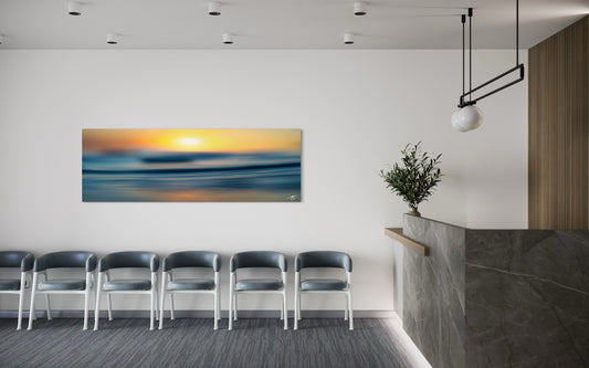 Modern office waiting area with a large wall art piece of a sunset over water.