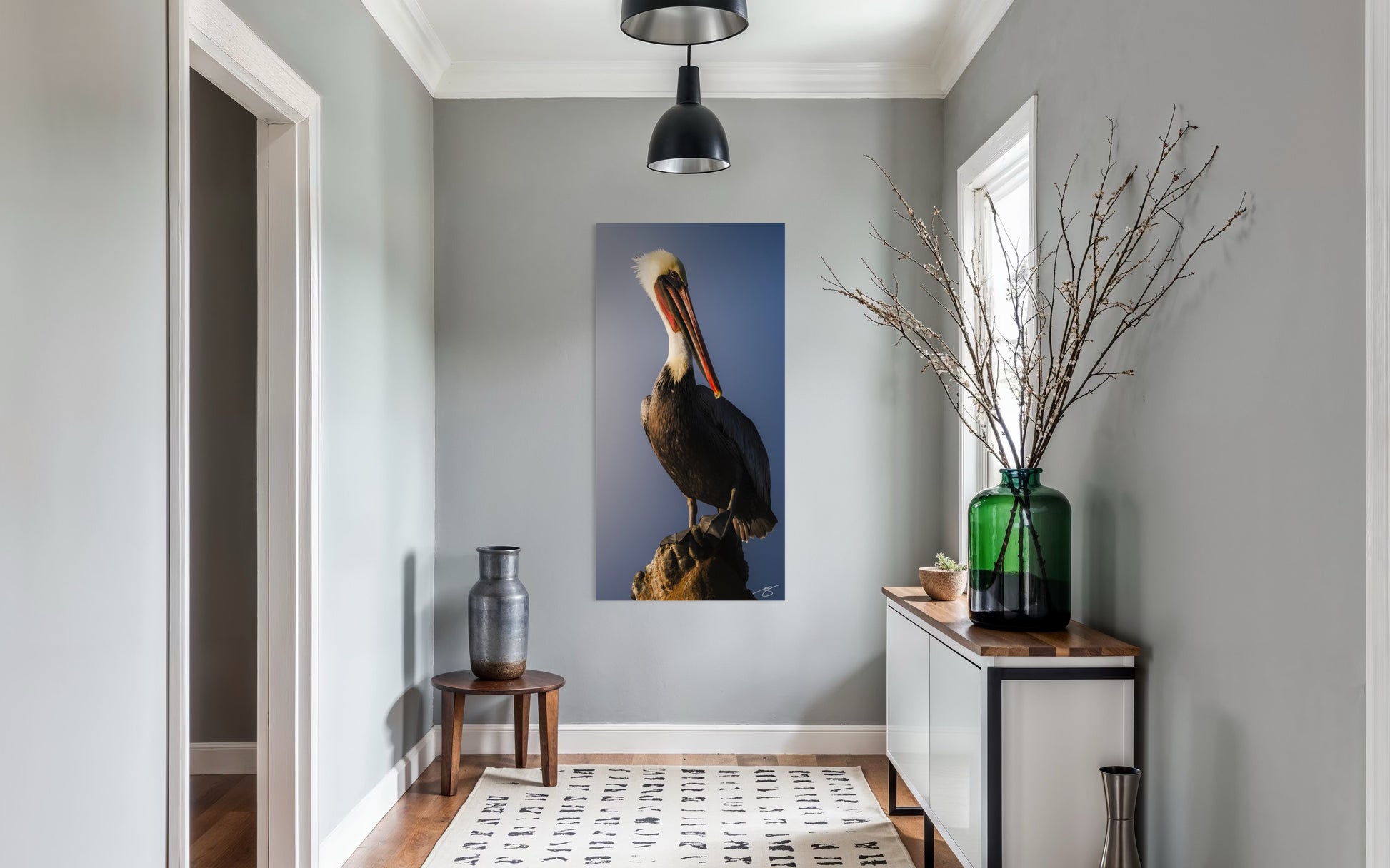 Modern interior hallway with a pelican artwork on the wall, a vase, and a plant.