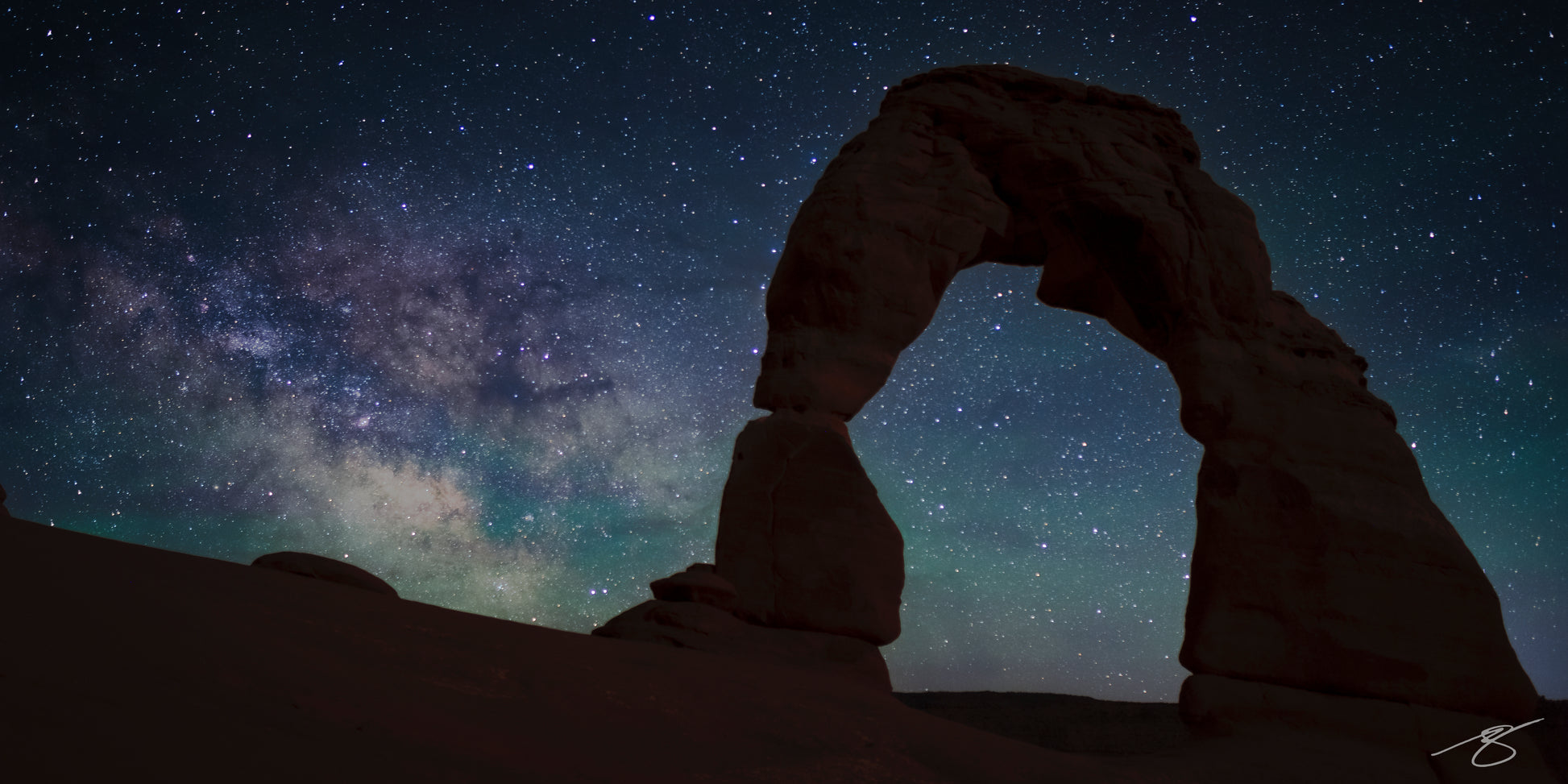 Starry night sky with a natural arch formation