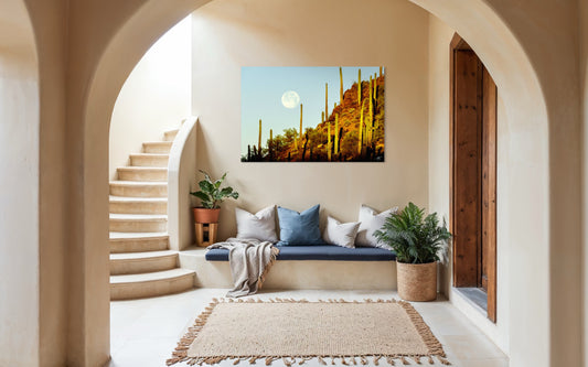 Full moon rising over tall saguaro cacti on a sunlit desert hillside in the Sonoran Desert during golden hour.