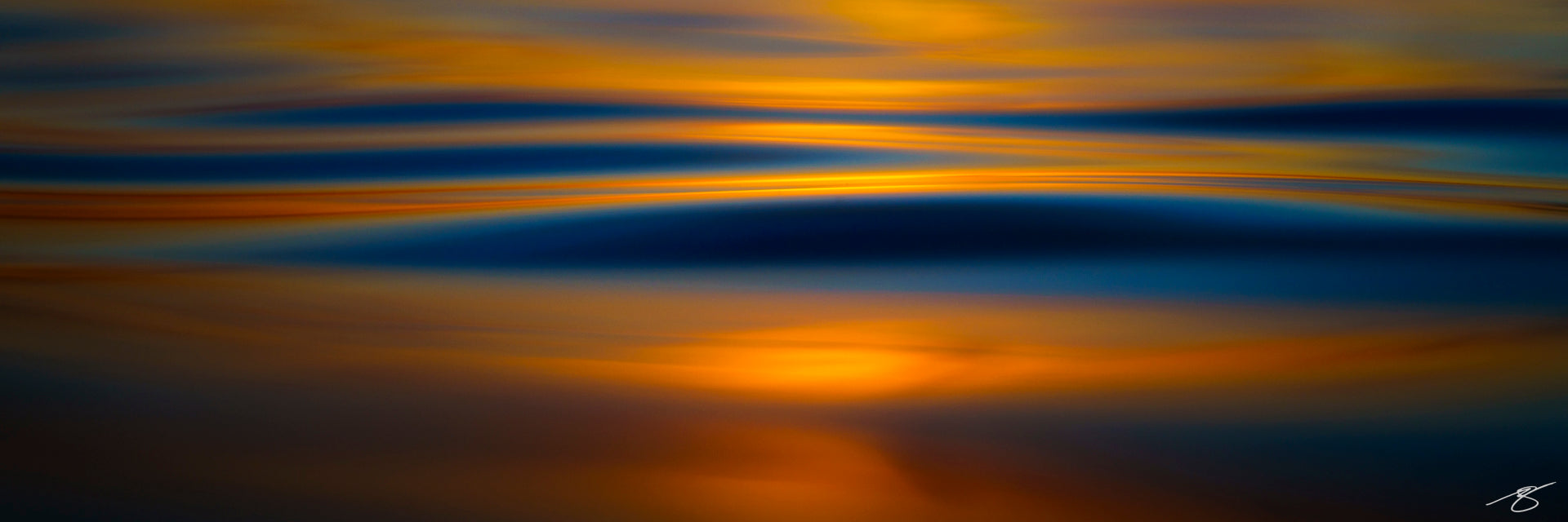 A minimalist abstract seascape showing deep blue ocean waves with warm golden reflections from the setting sun. The smooth, blurred motion creates layered horizontal bands of color, blending rich blue and molten gold to form a calming, modern coastal artwork.