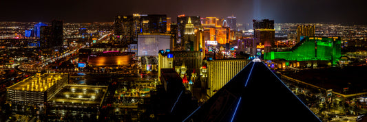 Fine art night panorama of the Las Vegas Strip captured from the Luxor Pyramid, showcasing glowing casinos, neon signs, wet streets, and expansive city lights stretching into the desert. A vibrant and dramatic urban cityscape under the night sky.