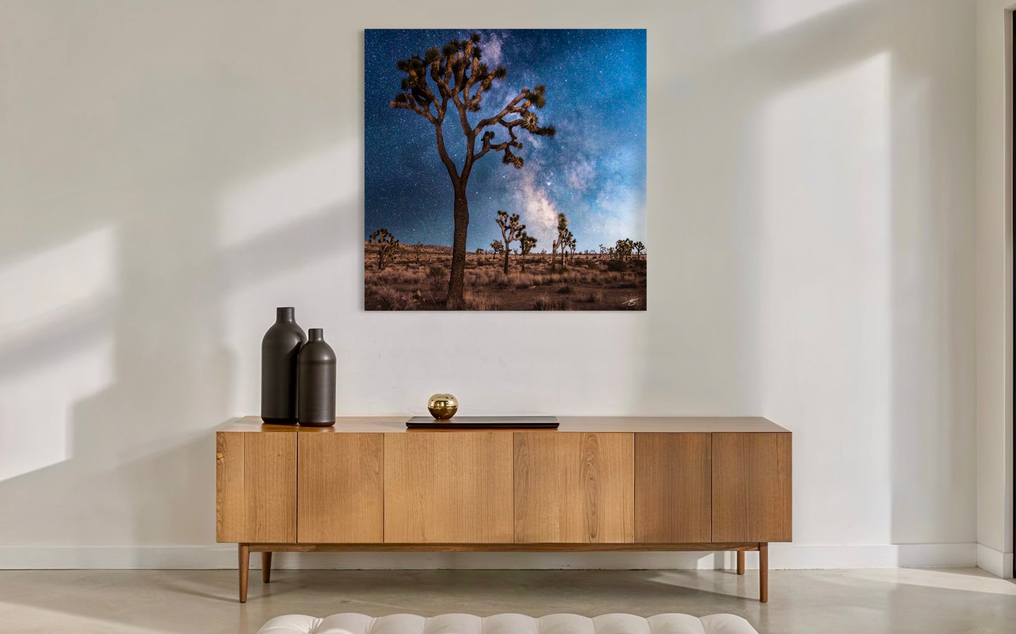 Wooden sideboard with decorative items against a wall with a large canvas print of a desert landscape.