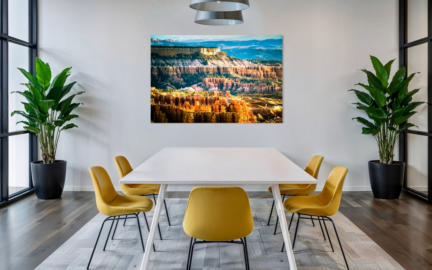 Modern dining room with a large wall-mounted canvas displaying a landscape, yellow chairs, and plants.