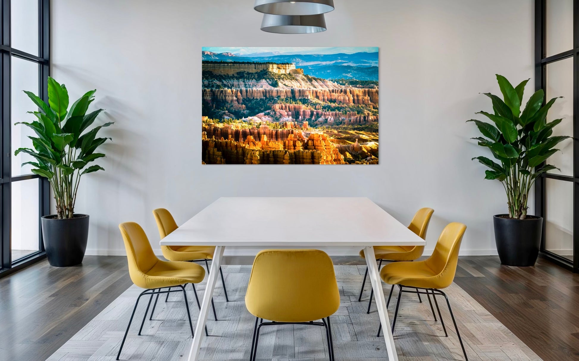 Modern dining room with a large wall-mounted canvas displaying a landscape, yellow chairs, and plants.