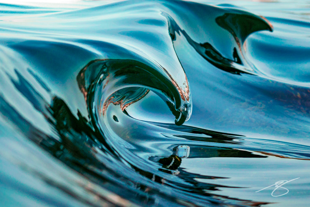 Close-up of a glassy micro wave curling into a smooth, teal ribbon with mirror reflections; abstract coastal fine art photograph