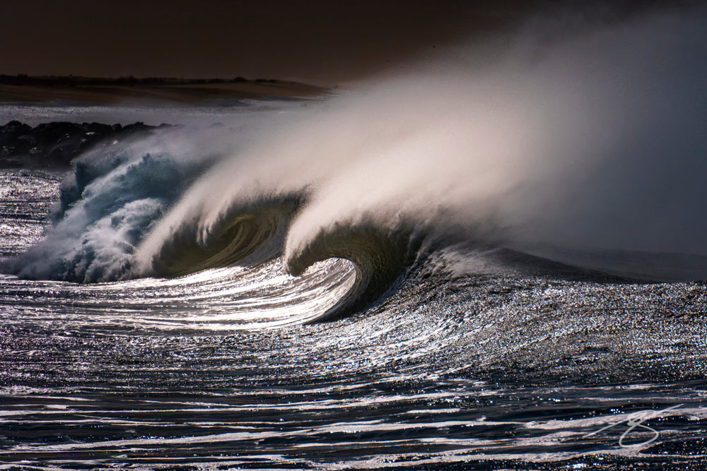 Power and elegance collide in this dramatic ocean photograph of a storm-driven wave curling into a perfect arc, its spray lit like silver against a dark sky. The textured surface and glowing backlight create a metallic sheen that adds movement and mood to any room. Ideal for modern, coastal, and minimalist interiors, this statement piece brings the raw energy of the sea to your wall.
