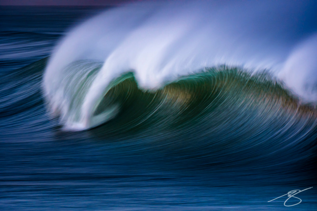 Long-exposure, panned photo of a breaking wave forming a smooth teal arc with a soft white spray; abstract ocean fine art photograph